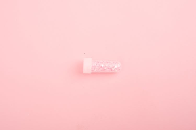 Glass Tube With Glitter On Pink Desk