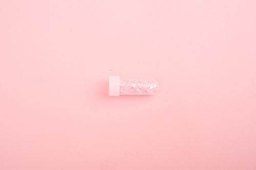 Free Top view of small glass laboratory test tube with shiny sparkles placed on pink background Stock Photo
