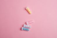 Top view of glass tubes filled with colorful sparkling star shaped glitter scattered on pink table