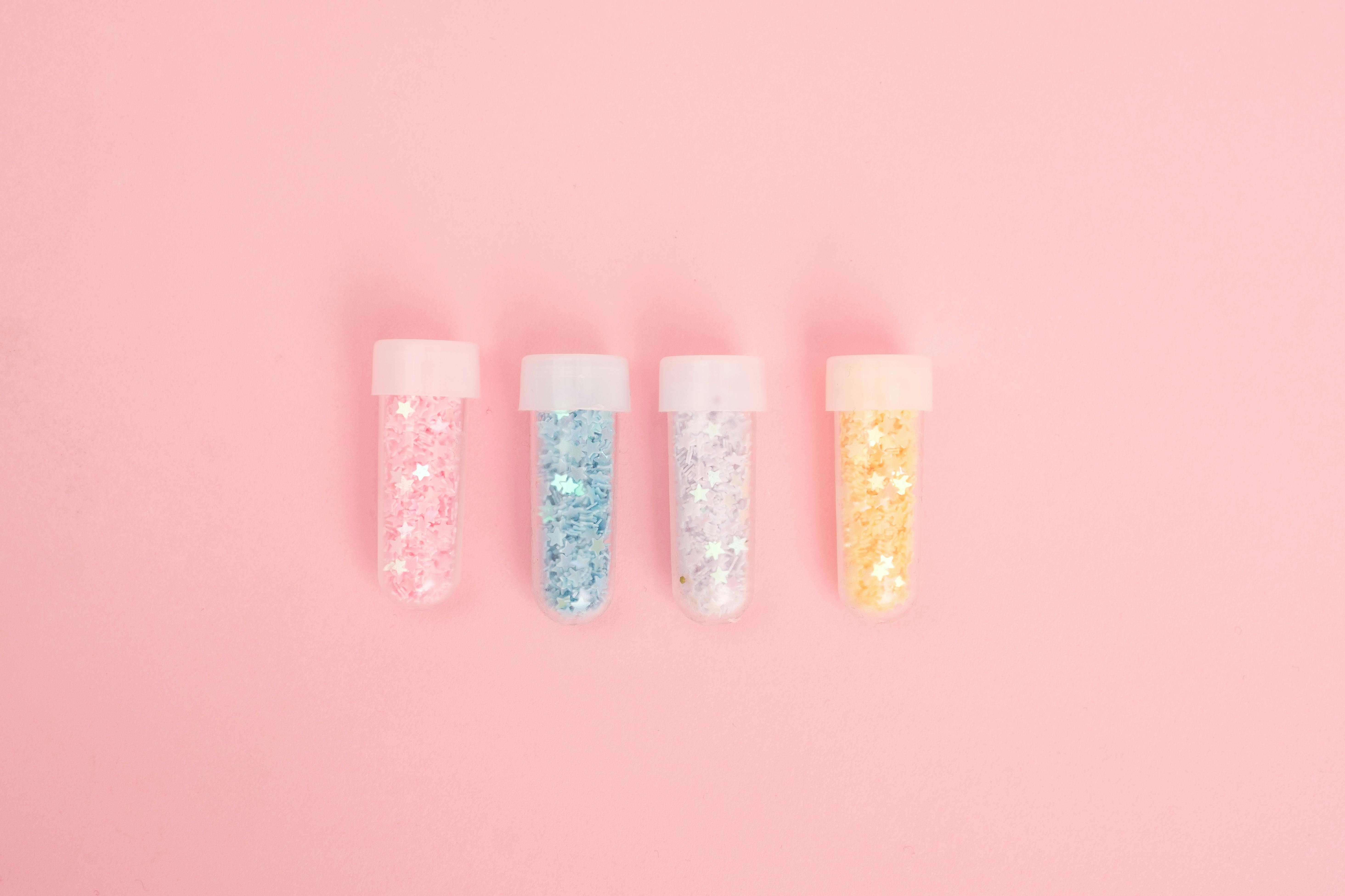 laboratory tubes with colorful glitter on pink desk