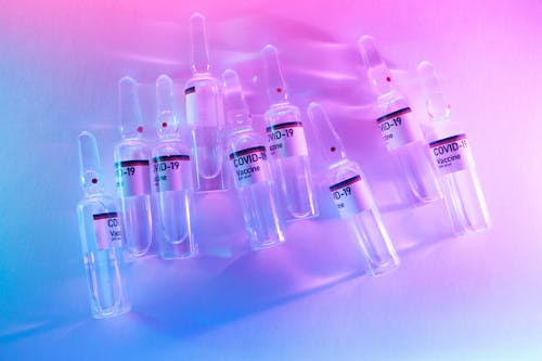 Free From above pile of doses of COVID 19 vaccine in similar ampoules placed on desk in laboratory with neon lights Stock Photo