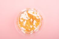 Top view of glass bowl filled with many capsules and pills for curing disease on pink background