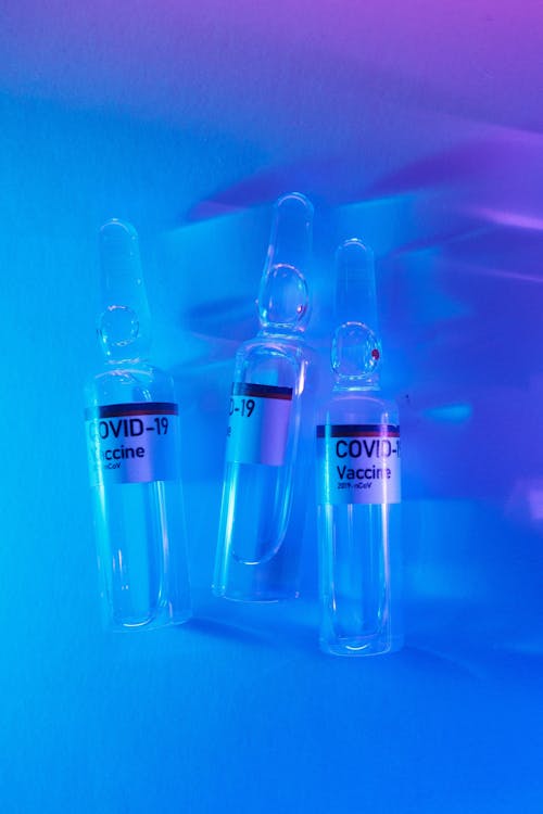 Top view of glass fragile ampoules with injection for COVID 19 in blue and purple light