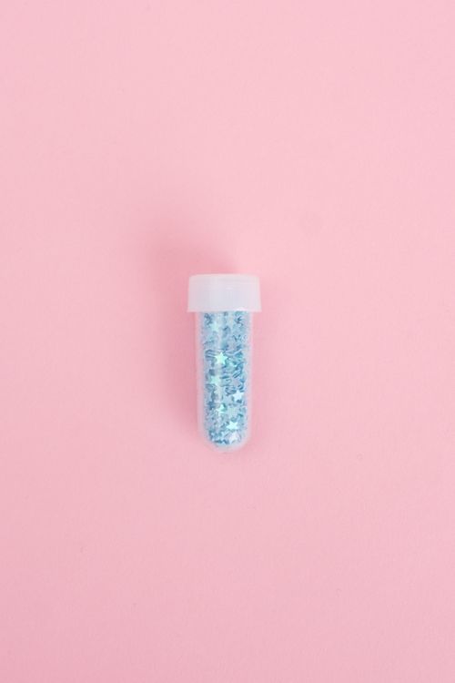 Free Top view of bright blinking glitter packed into glass tube on pink background Stock Photo