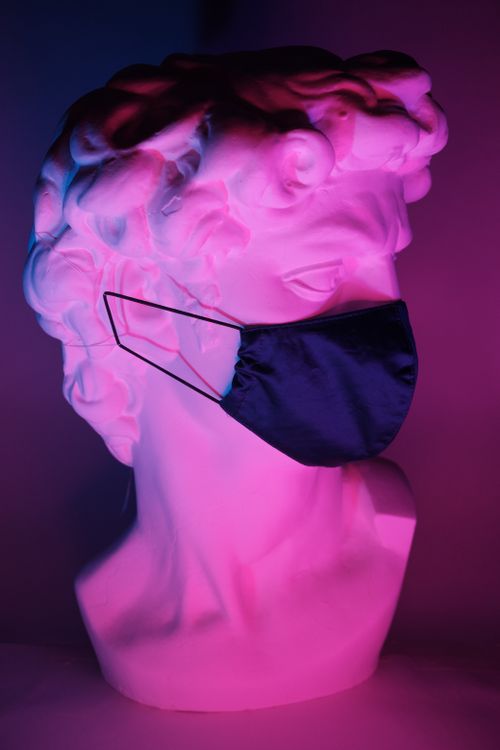 Free Bust of Apollo in black medical mask in dark room with purple light Stock Photo