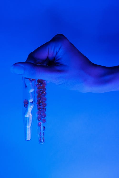 Transparent vials with various pills and capsules for illness in bright blue ultraviolet light