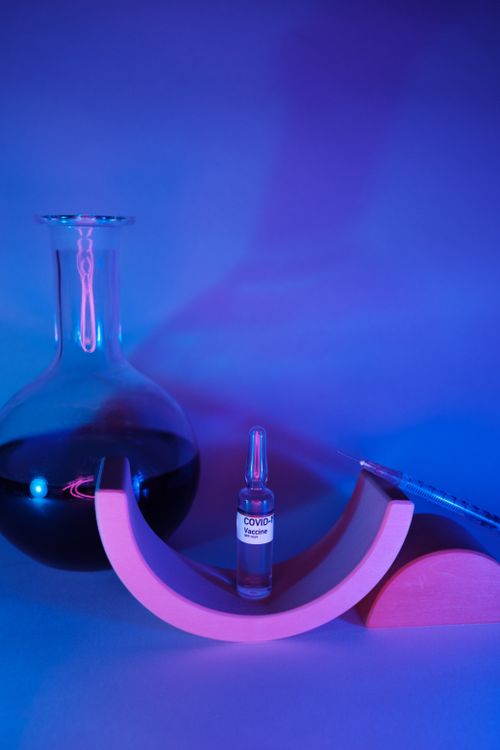 Free Vaccine for coronavirus prepared for injection near glass flask with liquid and syringe on geometrical figures Stock Photo