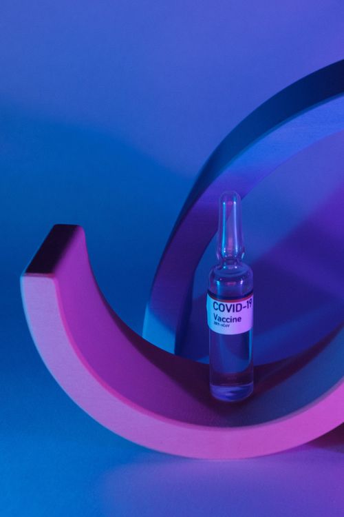 Free Glass ampoule with vaccine for coronavirus on geometrical figure in blue ultraviolet light Stock Photo