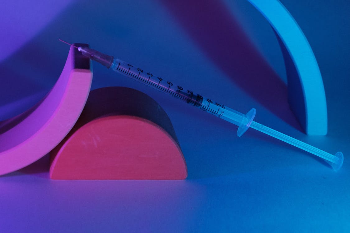 Free Medical syringe on geometrical figures in ultraviolet light Stock Photo