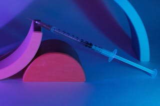 Medical syringe on geometrical figures in ultraviolet light