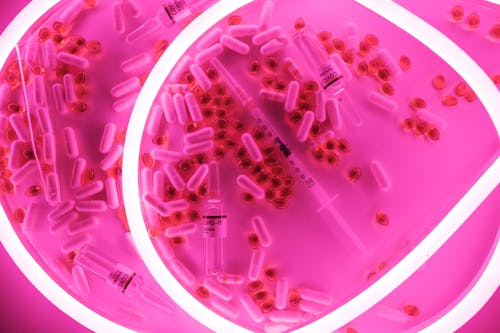 Medical syringe and pills with capsules placed in bright light