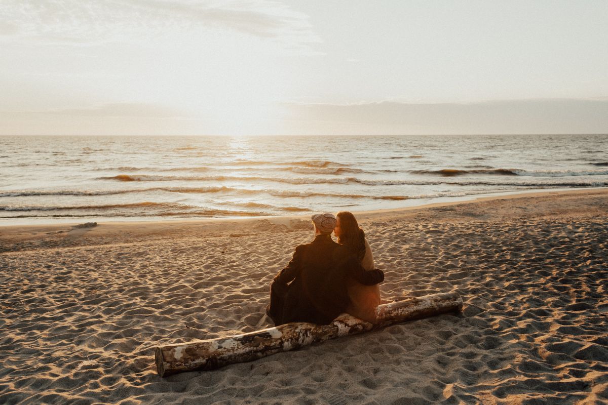 Stel zit samen op een strand bij zonsondergang