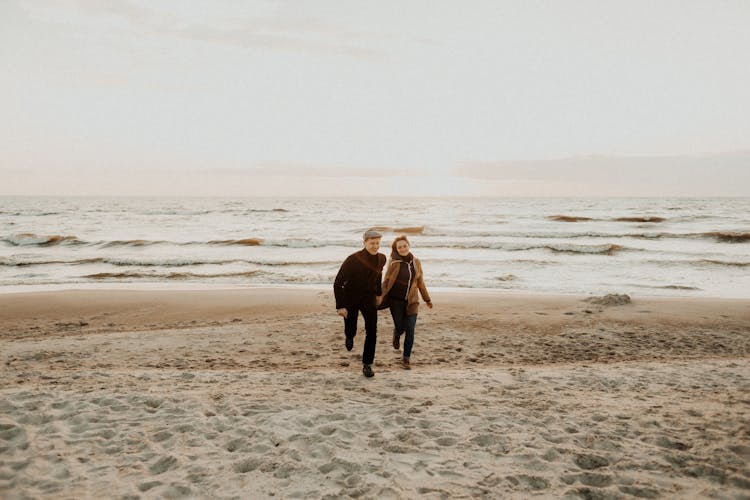 A Couple Running On A Beach