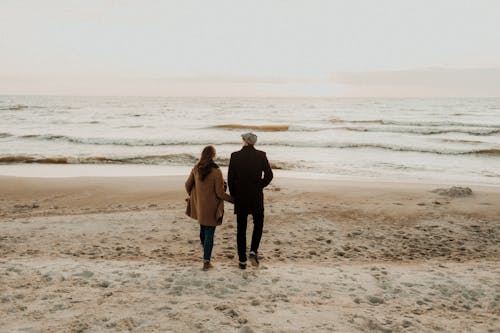 Free Man and Woman Walking at the Beach Stock Photo