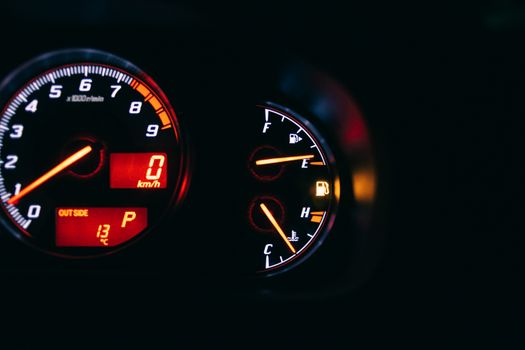 Modern control and measuring devices with arrows indicating numbers and letters on scales in automobile on black background
