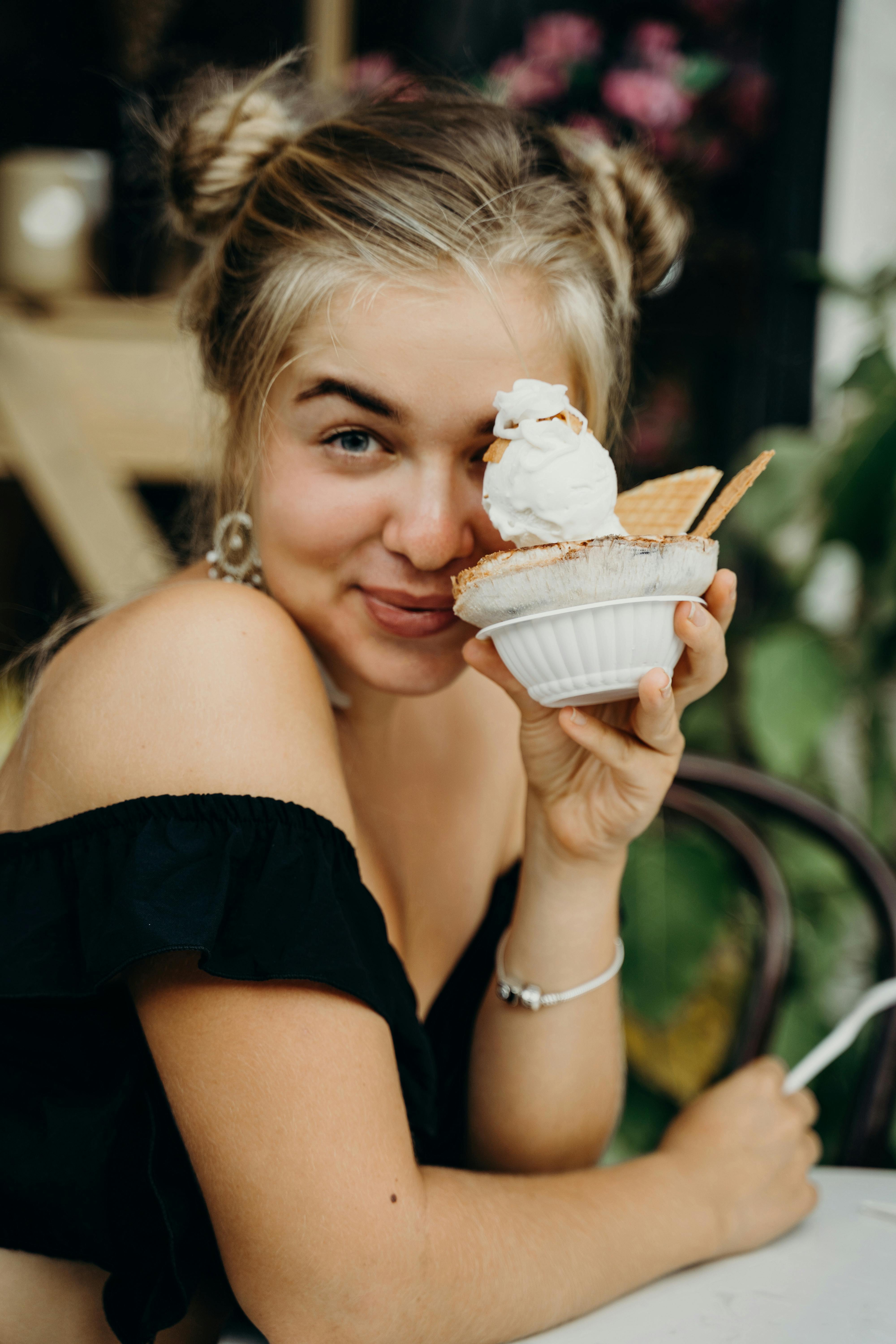 Young woman enjoying a dessert in a Bali cafe, showcasing a delightful ice cream treat.