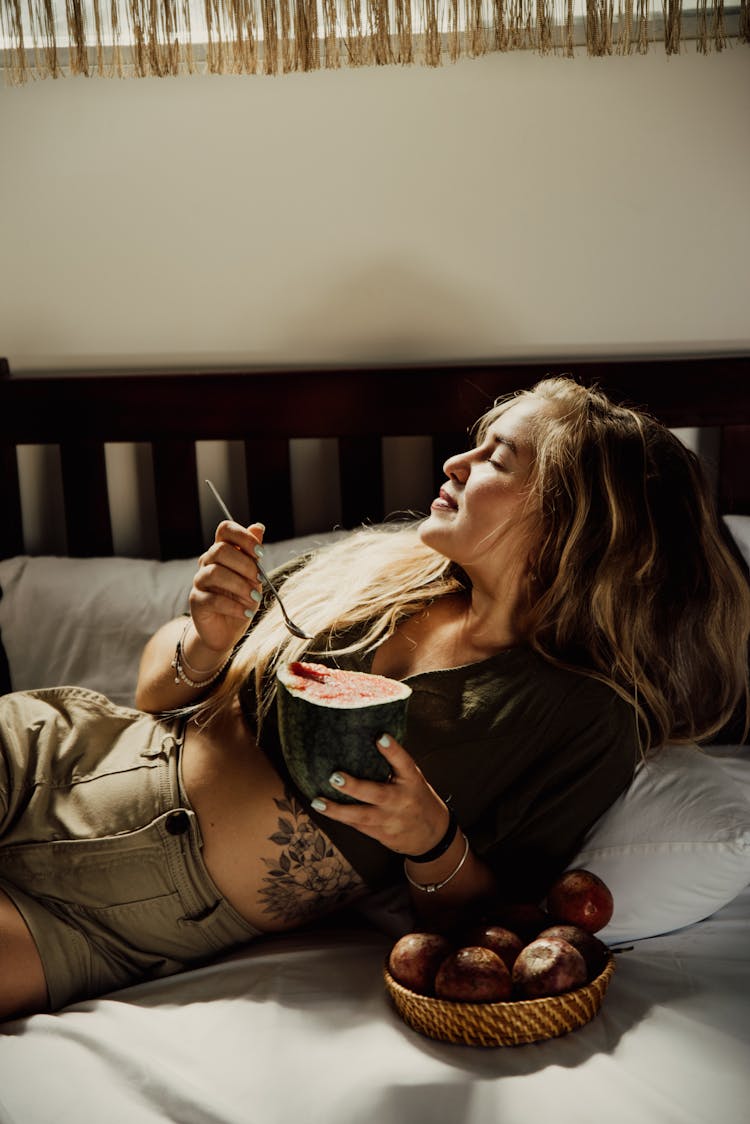 
A Woman Eating A Watermelon In Bed