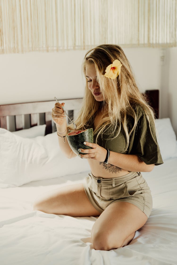 A Woman Eating A Watermelon In Bed