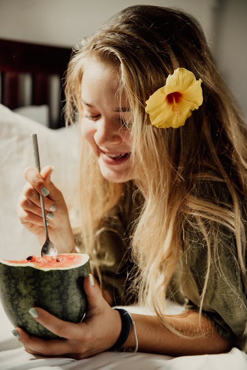 Free Woman in Green Sweater with Yellow Flower Eating Watermelon Stock Photo