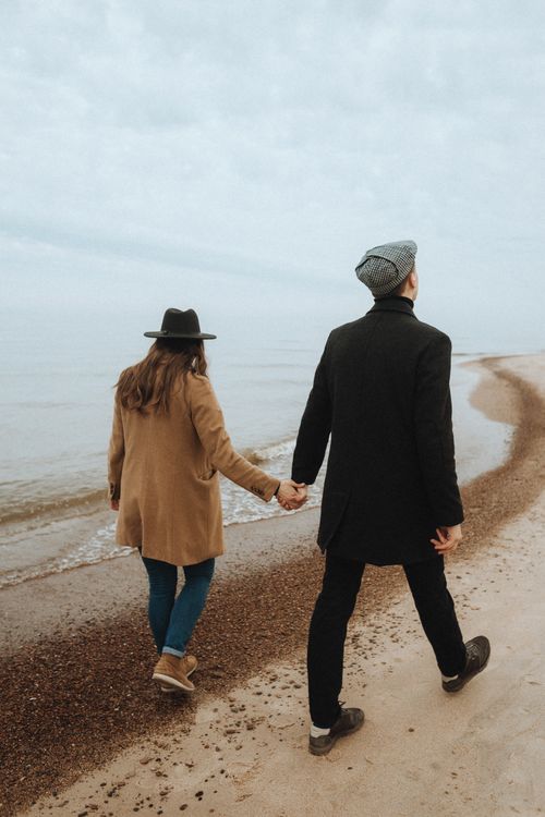 Free A couple walks hand in hand along a serene beach, capturing a moment of romance and togetherness. Stock Photo