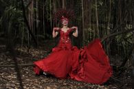 Woman in Red Dress Sitting on Ground Surrounded by Green Plants