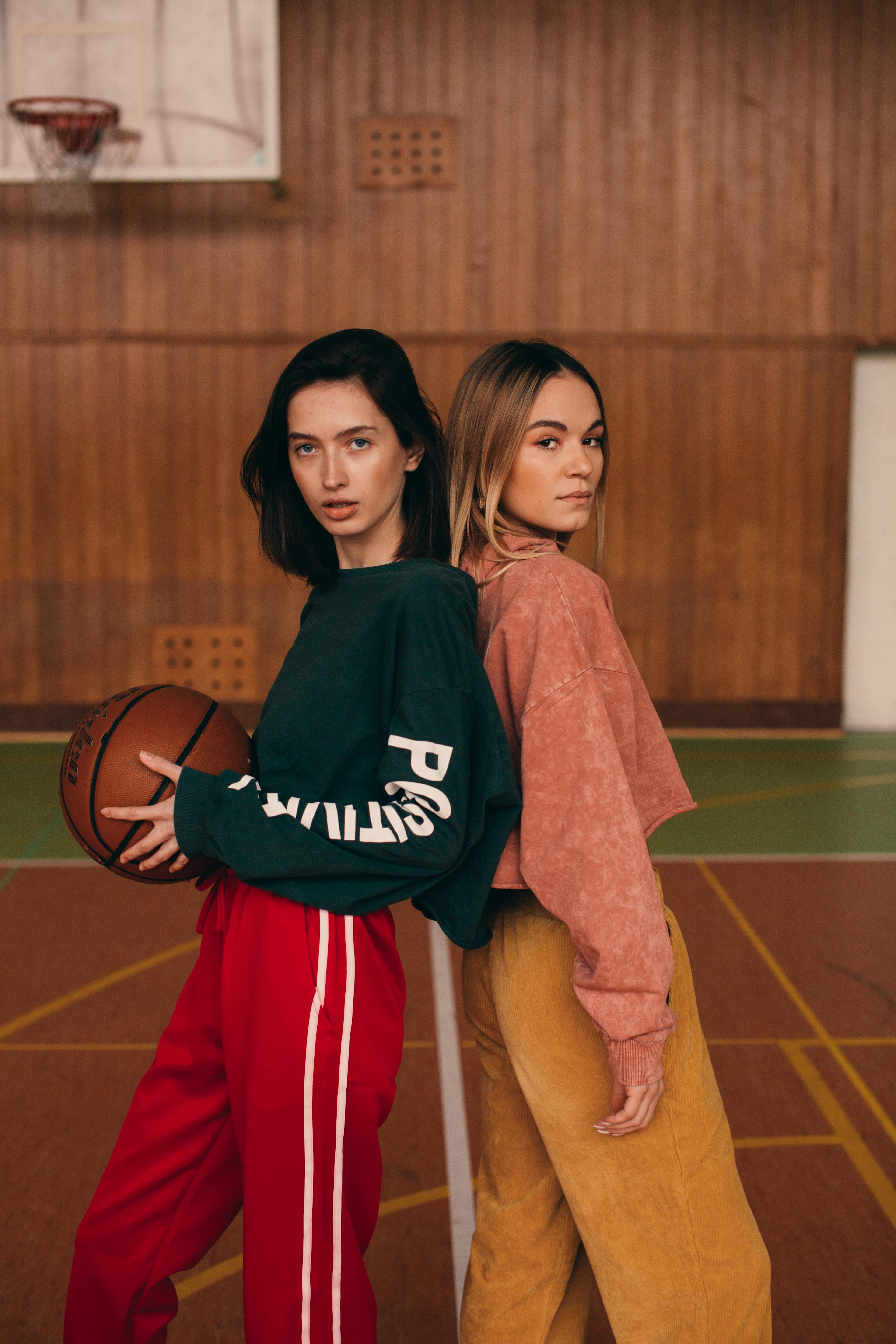 women leaning against each other on a basketball court