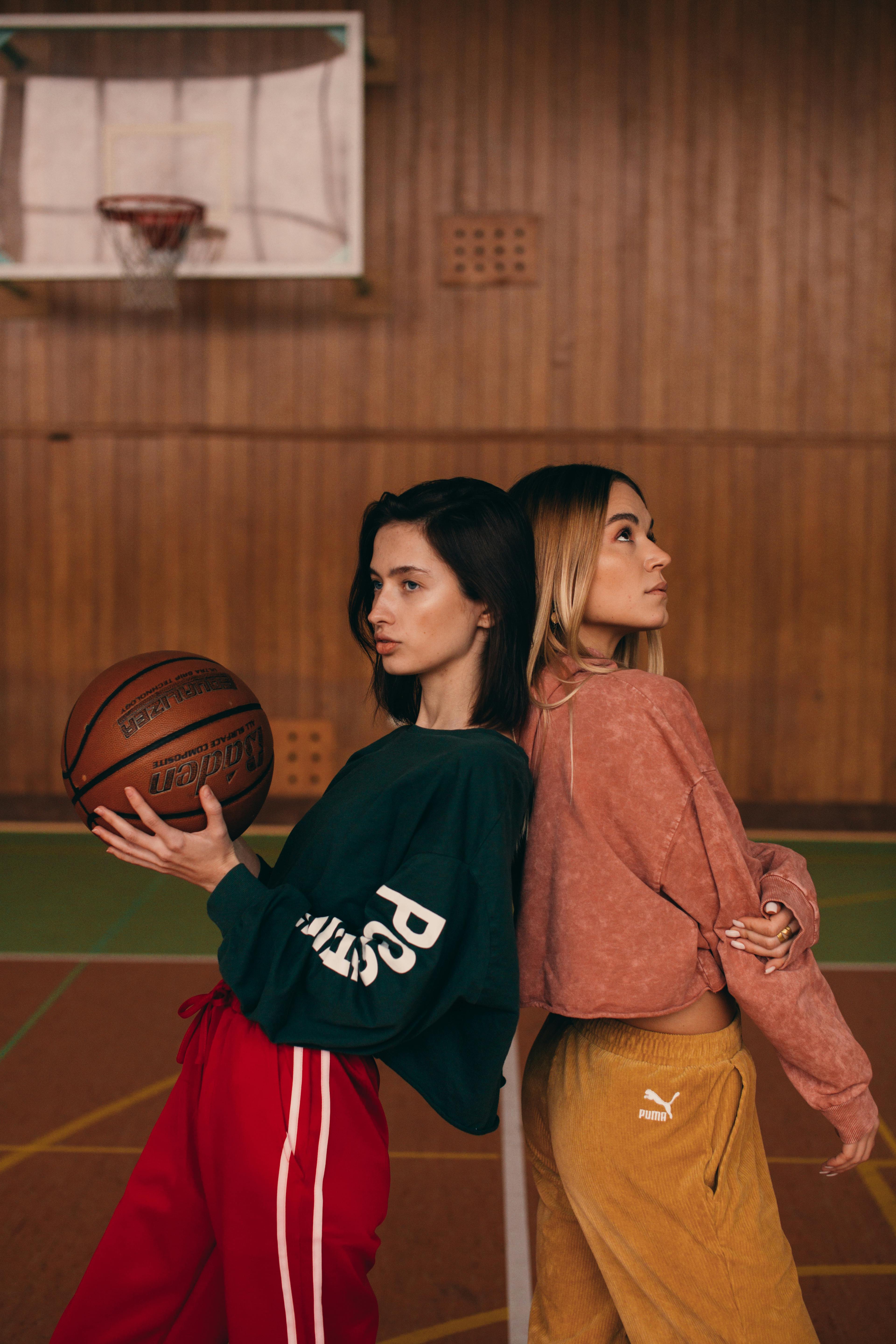 women leaning against each other on a basketball court