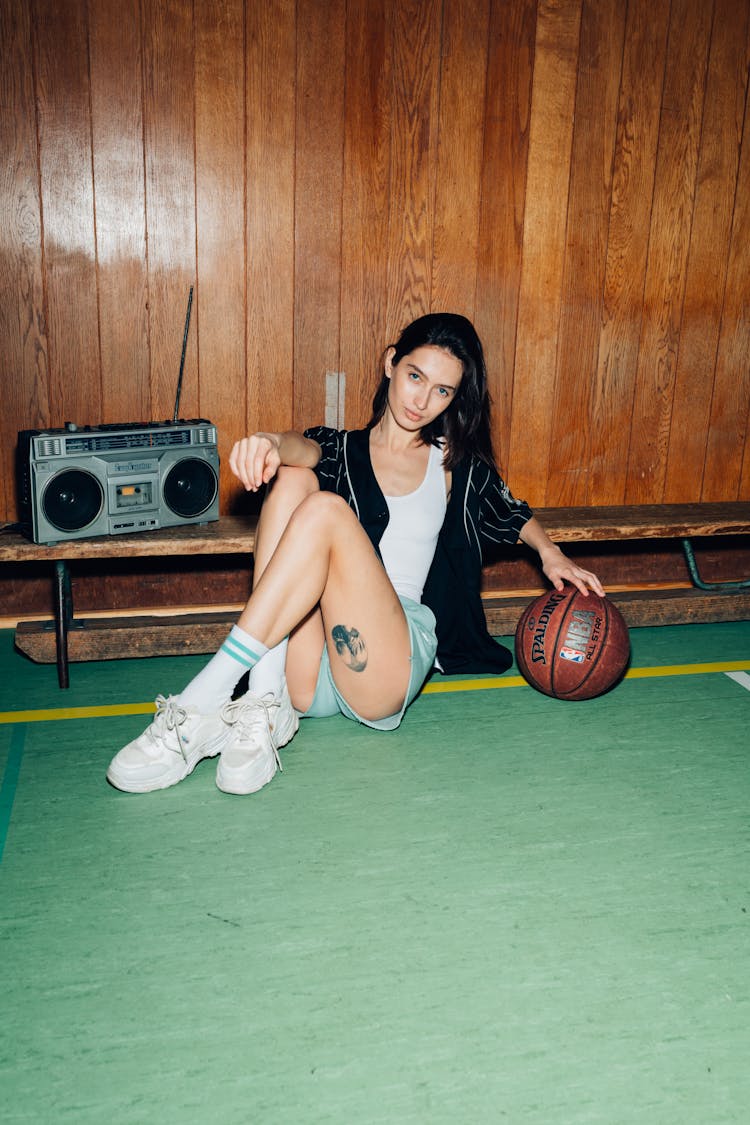 Stylish Woman Sitting On Playground With Ball