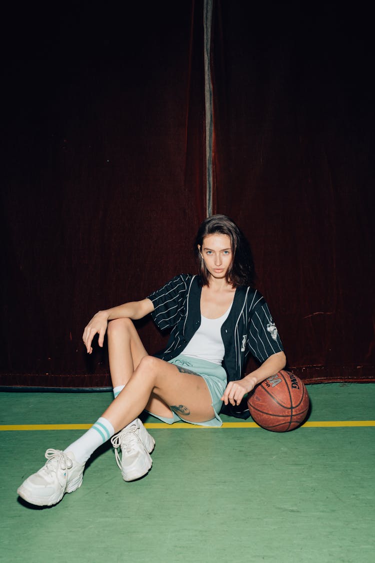 Woman Wearing A Jersey Sitting With Basketball