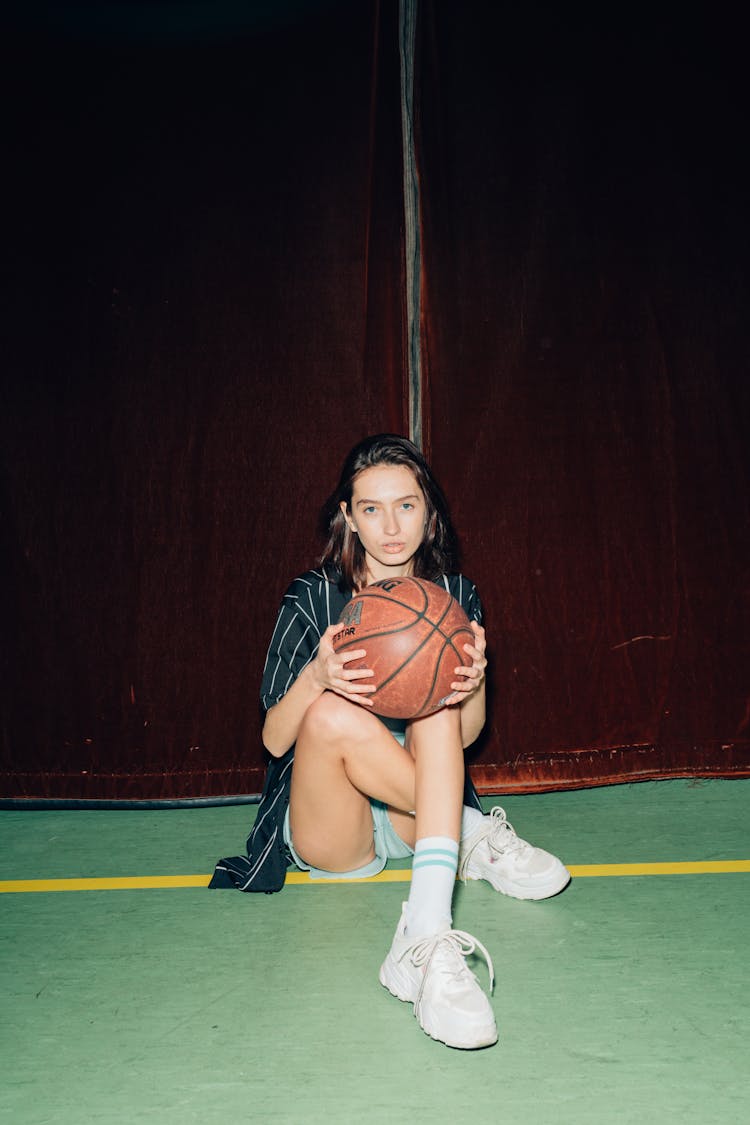 Woman Sitting Holding A Basketball
