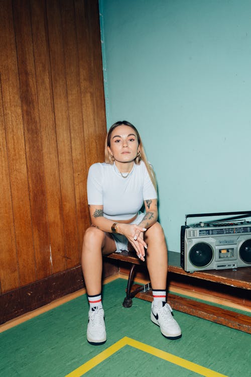 A Woman Sitting on a Wooden Bench Beside a Cassette Player