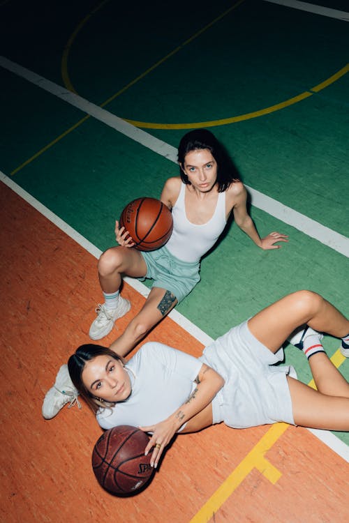 Free A Pair of Women Holding Balls on Basketball Court Stock Photo
