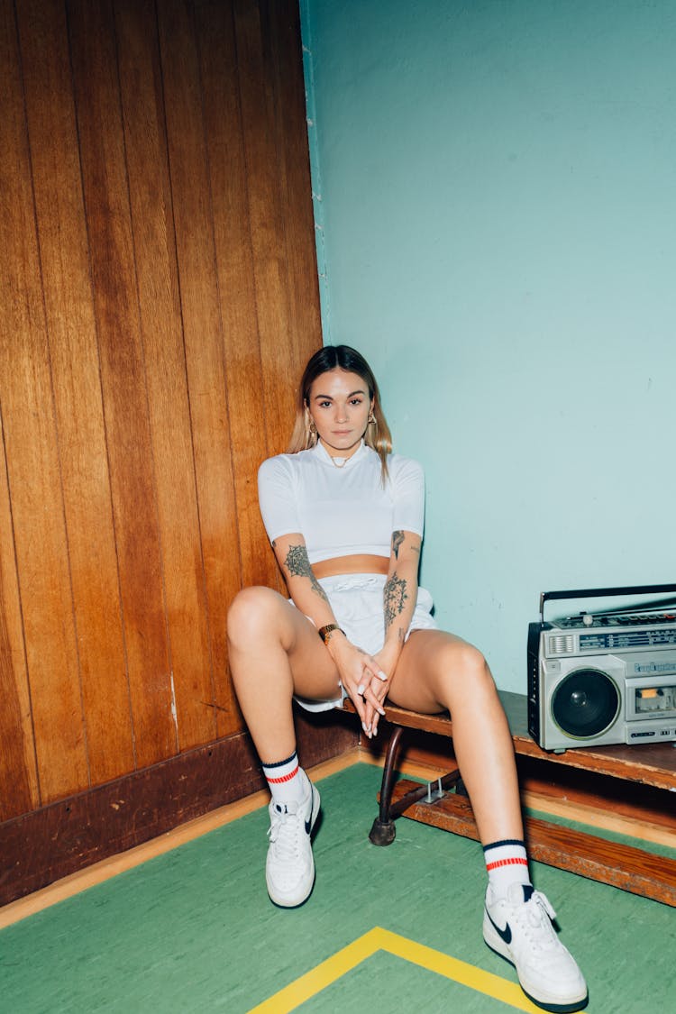 Woman Sitting On A Wooden Bench Beside A Stereo