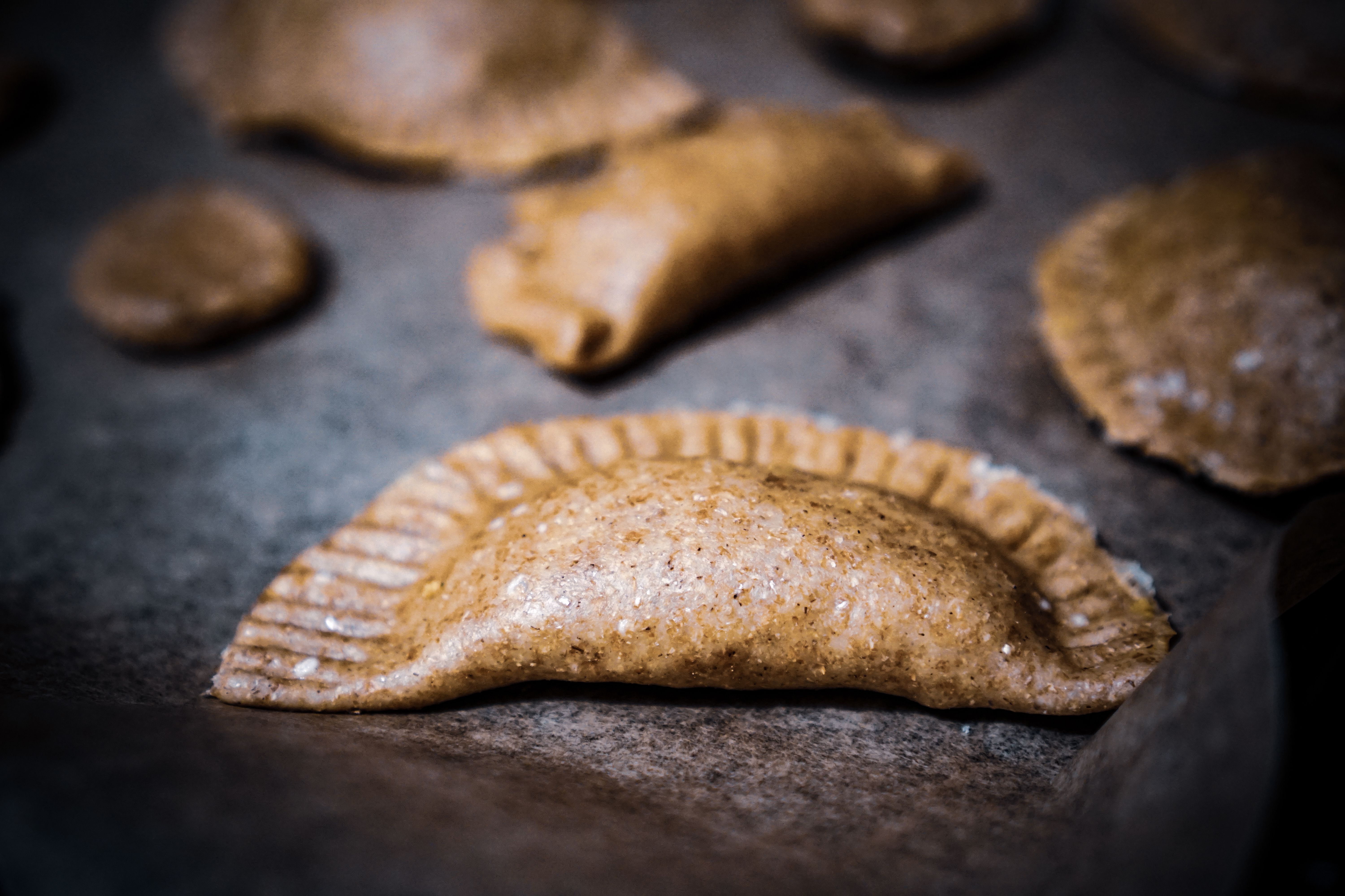 Appetizing close-up of freshly made dumplings on a baking tray, showcasing texture and detail.