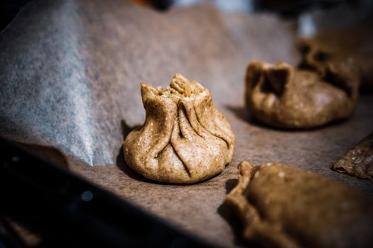 Close-up of rustic homemade dumplings on parchment-lined baking sheet, showcasing rich texture and detail.
