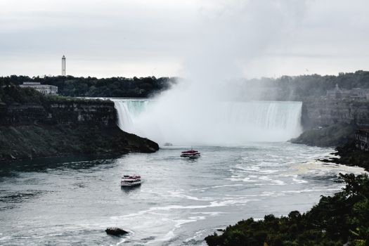 A stunning capture of Niagara Falls with tour boats cruising the waters, showcasing nature's grandeur.