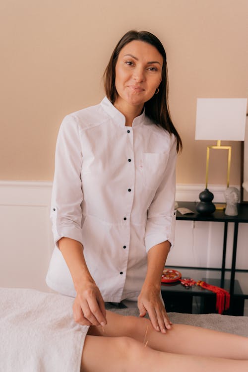 Free A Woman in White Button Up Shirt Standing Beside a Person Lying Down Stock Photo