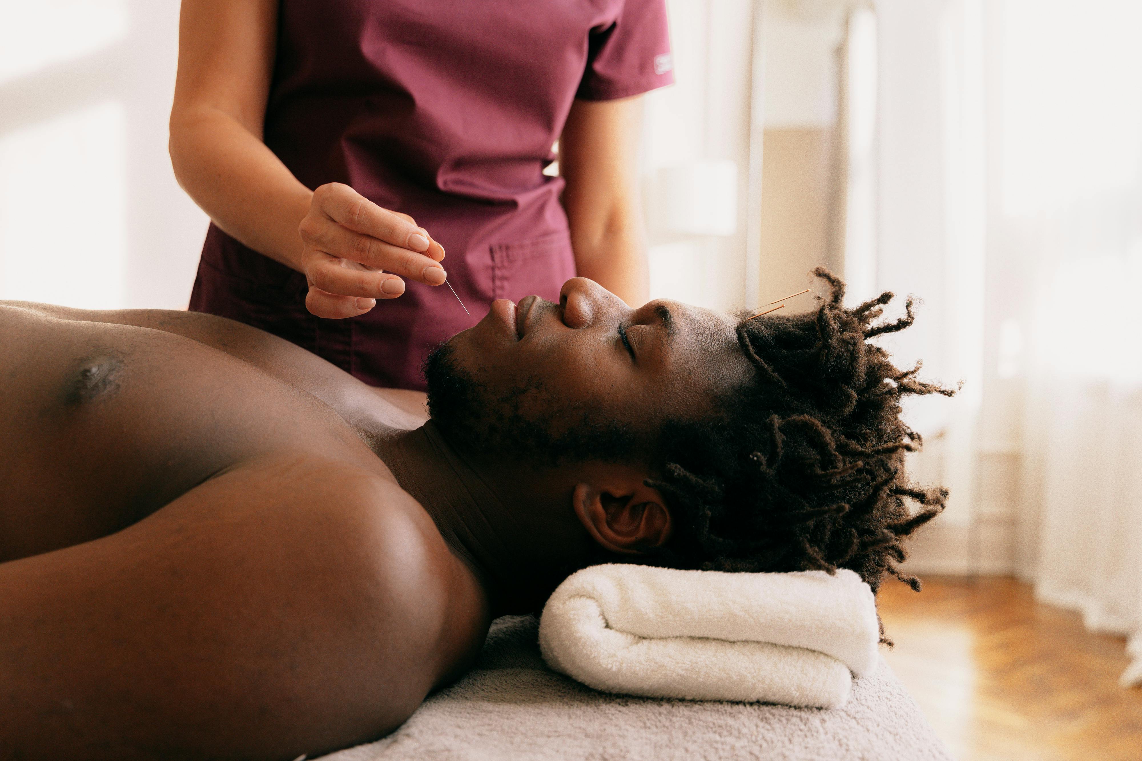 a person holding needles near a man s chin