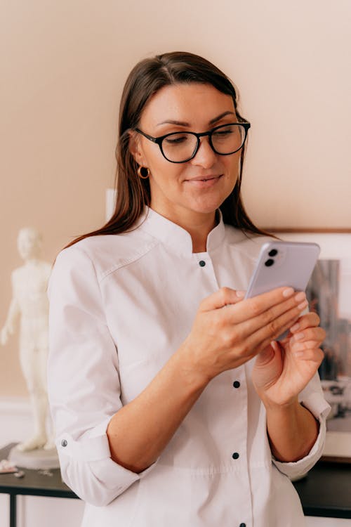 A Woman Wearing Eyeglasses Using Her Smartphone