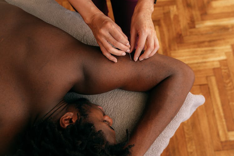 A Woman Inserting A Needle Lying On A Man's Arm