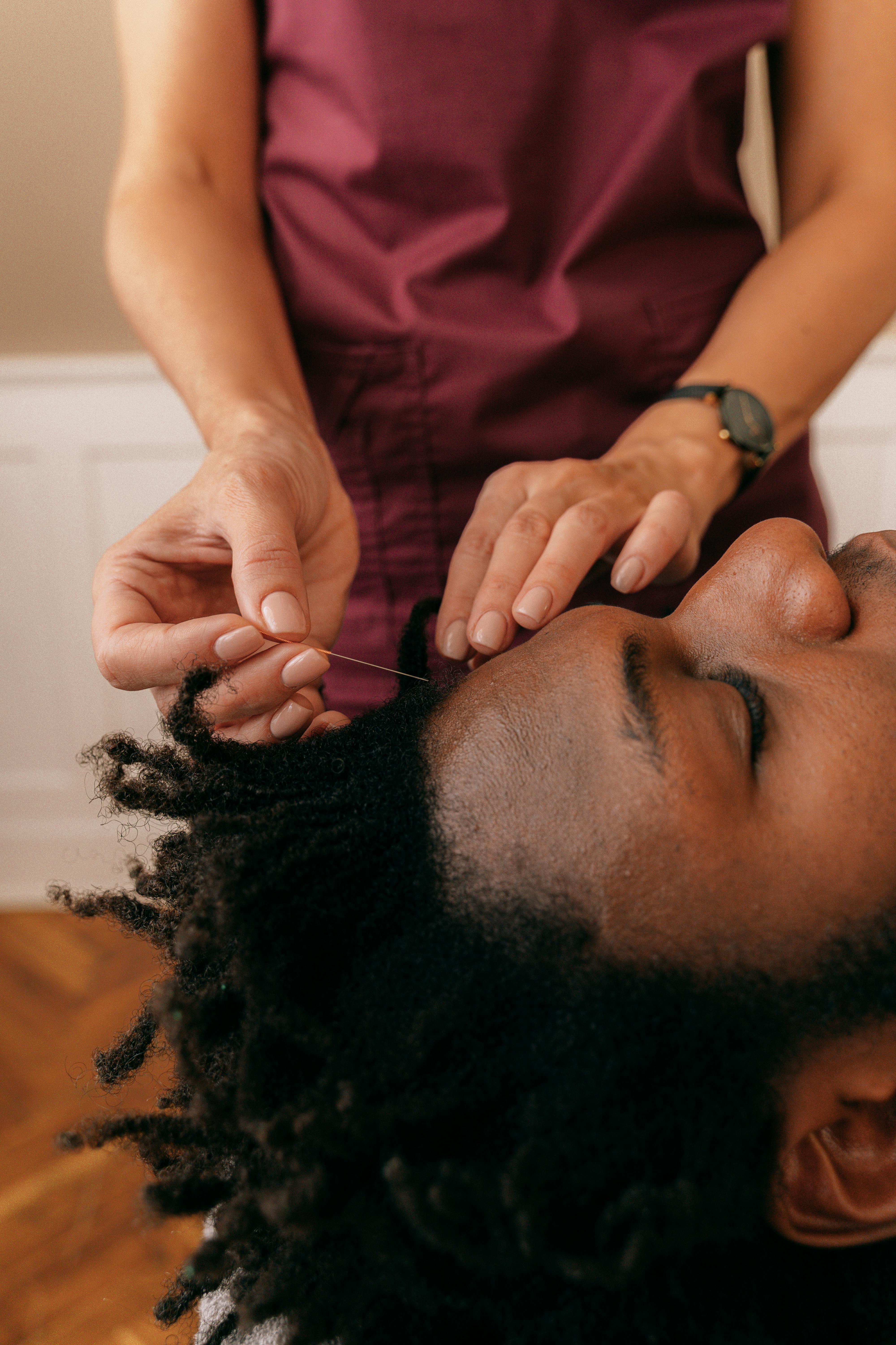 a person inserting needle on a man s forehead