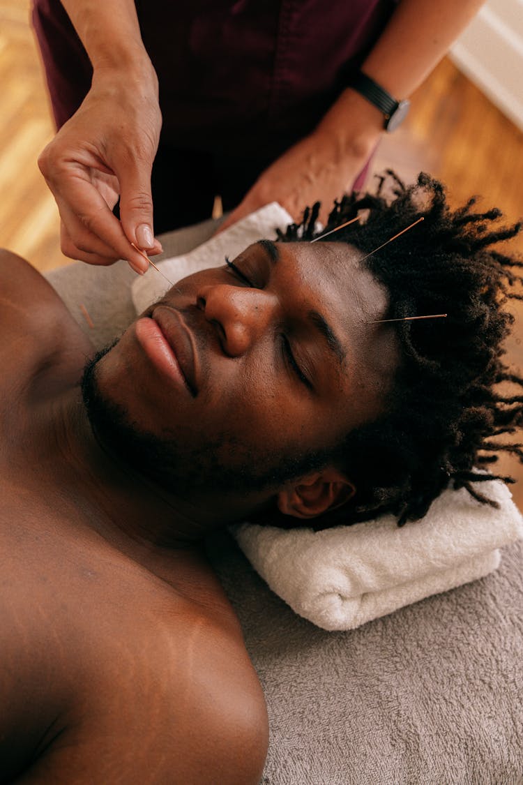 A Person Inserting Needle On A Man's Cheek