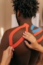 A Person Putting Kinesio Tape on Man's Back