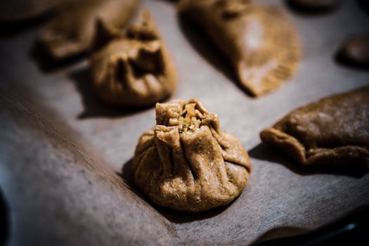 Close-up of rustic homemade dumplings on parchment, showcasing intricate wrapping and texture.