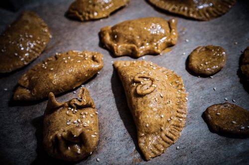 Free Close-up of homemade pastries with sesame seeds on parchment paper, ready to bake. Stock Photo