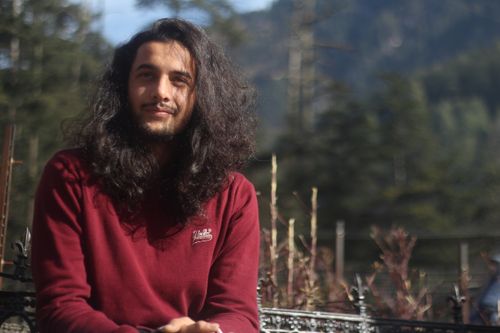 Free A relaxed outdoor portrait of a man with long hair and a beard wearing a red sweater. Stock Photo