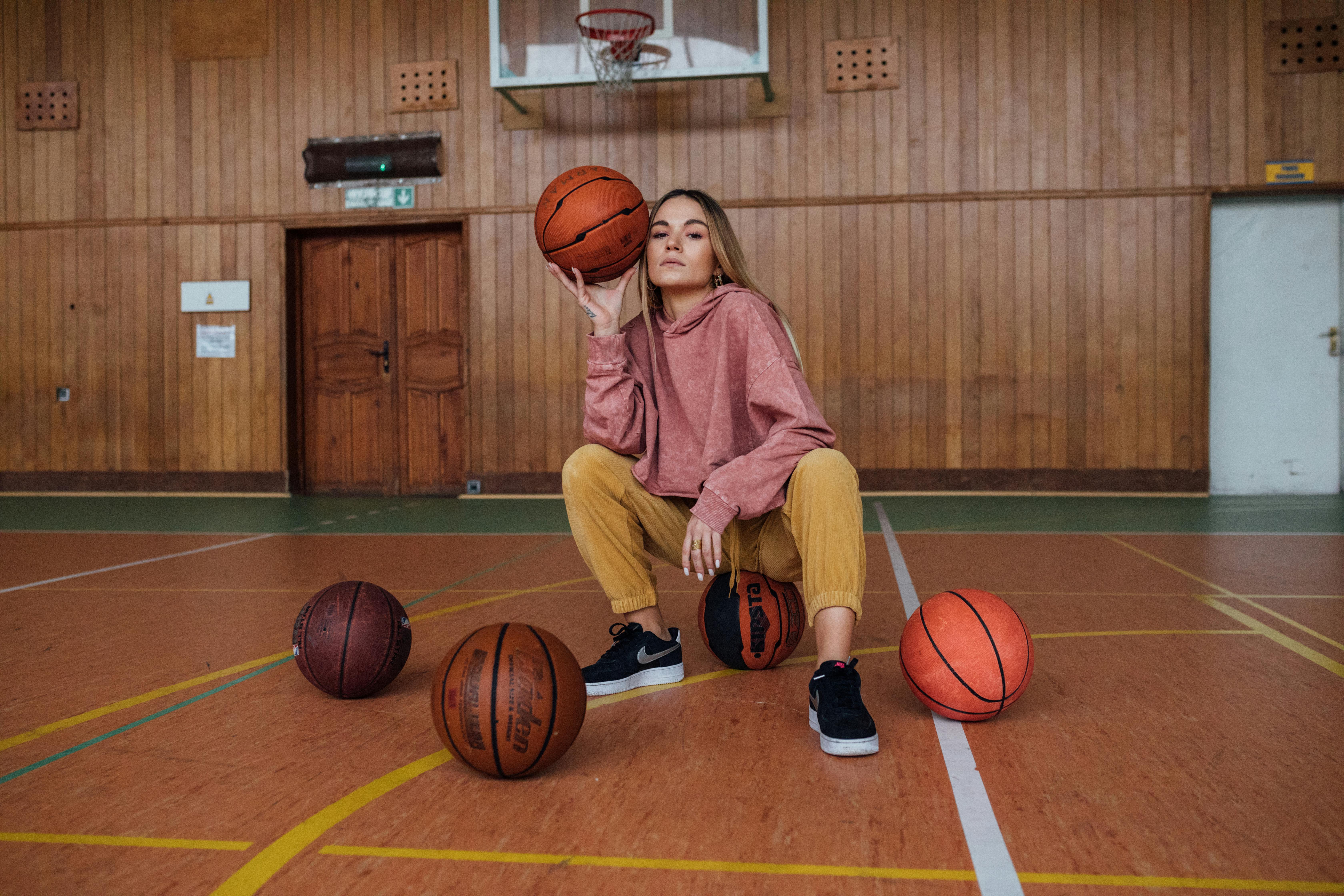 woman in pink sweater sitting on a basketball