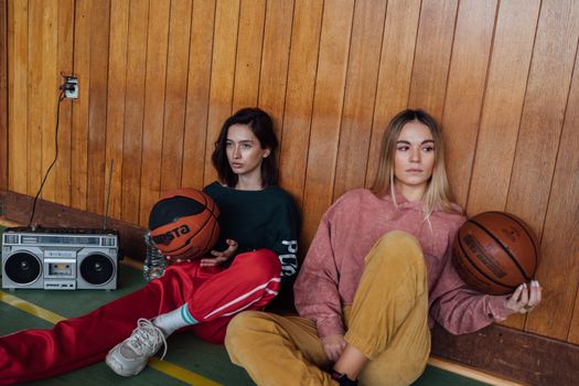 Two women with basketballs and a boombox, featuring a retro sporty aesthetic.