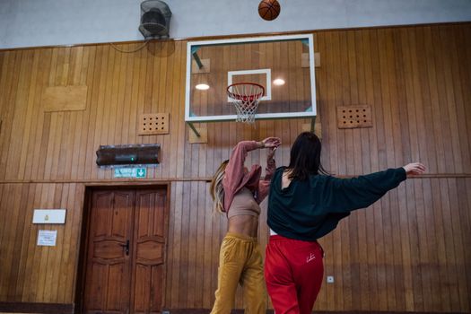Two women playing basketball indoors, capturing a competitive moment.