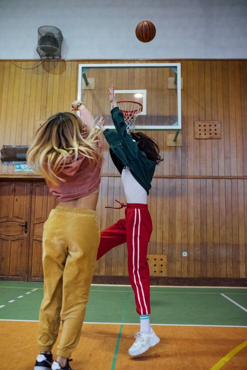Free Dynamic shot of two women jumping for a basketball indoors. Stock Photo